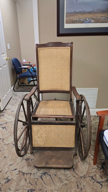 Antique wooden wheelchair on carpeted floor