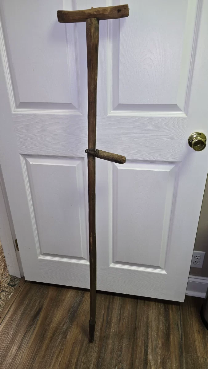 Antique handmade wooden crutch with pivoting hand rest and metal tip