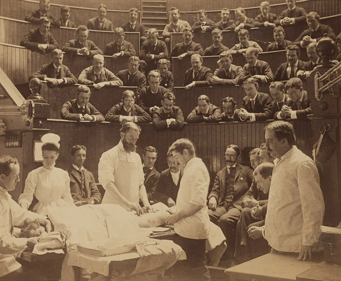 Historical medical lecture theatre with students observing surgery