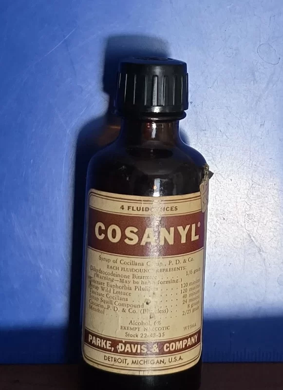 Vintage Cosanyl cough syrup bottle with label showing narcotic and botanical ingredients.