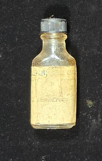Vintage bottle of Oil of Sassafras with yellowed label and screw cap, containing preserved liquid.