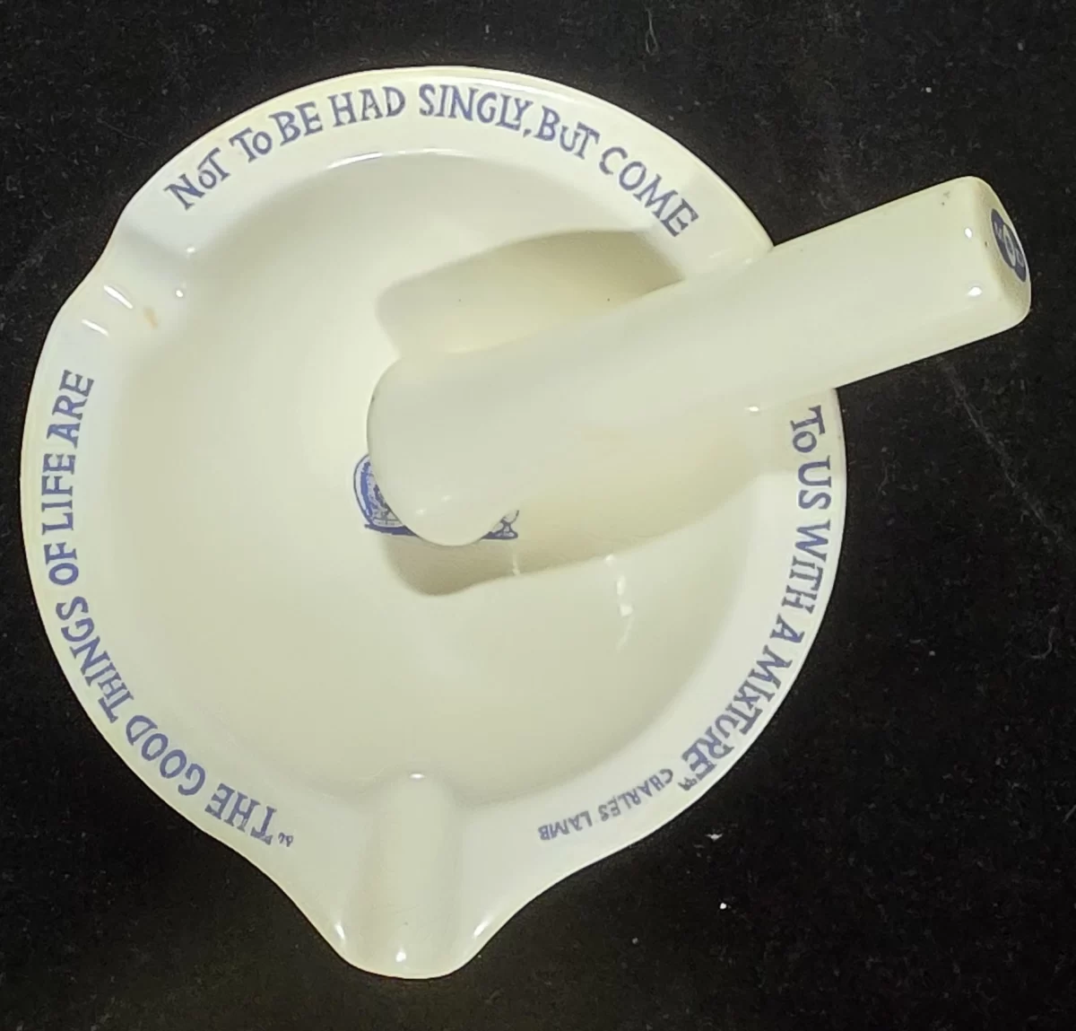 Mortar with pestle resting across it, showcasing both the ceramic finish and aphorism.