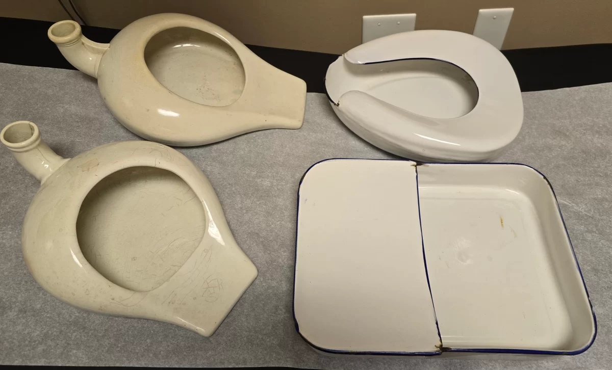 Group photo of four antique bedpans including enamel and porcelain examples side by side