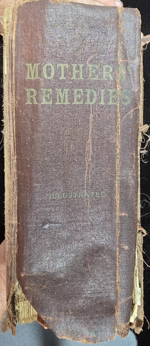 Worn spine of 1919 copy of Mother’s Remedies showing title in faded gold print.