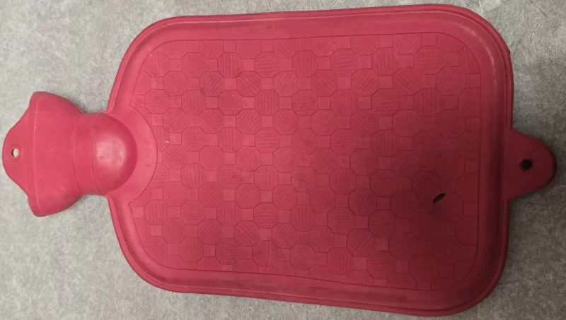 Top view of vintage rubber hot water bottle with red textured surface