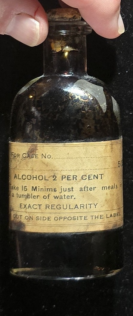 Vintage prescription bottle labeled Alcohol 2 Percent with cork stopper and dosage instructions