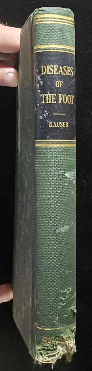 Green cloth hardcover of Diseases of the Foot by Emil D. W. Hauser, M.D., with fraying at the spine and gold-embossed title on the black label.