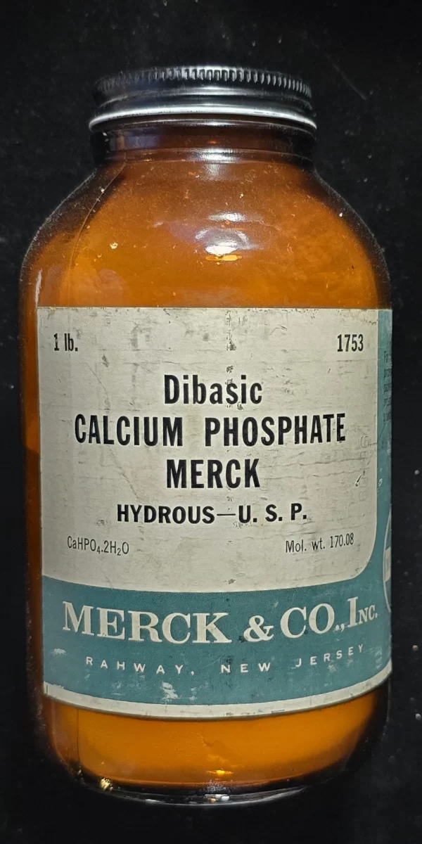 Vintage Merck & Co. bottle labeled Dibasic Calcium Phosphate, Hydrous U.S.P., filled with original orange powder