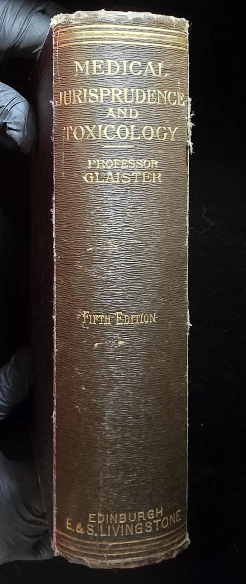 Brown textured spine of the Glaister forensic textbook, showing gilt-stamped title “Medical Jurisprudence and Toxicology,” author name, edition, and publisher.