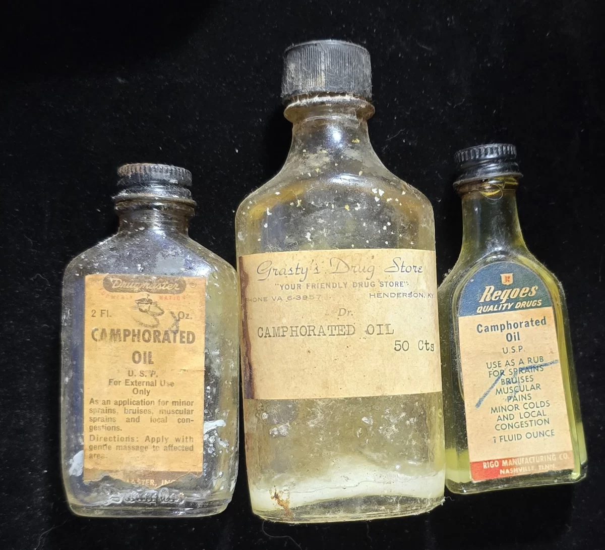 hree vintage camphorated oil bottles with original pharmacy and commercial labels, circa 1930s–1950s.
