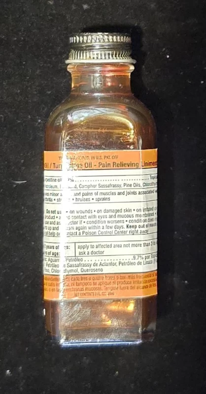 Front view of amber glass bottle labeled “Volcanic Oil / Turpentine Oil – Pain Relieving Liniment.”