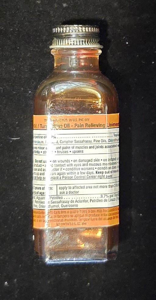 Front view of amber glass bottle labeled “Volcanic Oil / Turpentine Oil – Pain Relieving Liniment.”