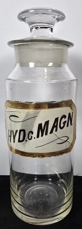 Large antique apothecary jar labeled HYD c MAGN with glass stopper, clear glass pharmacy container.