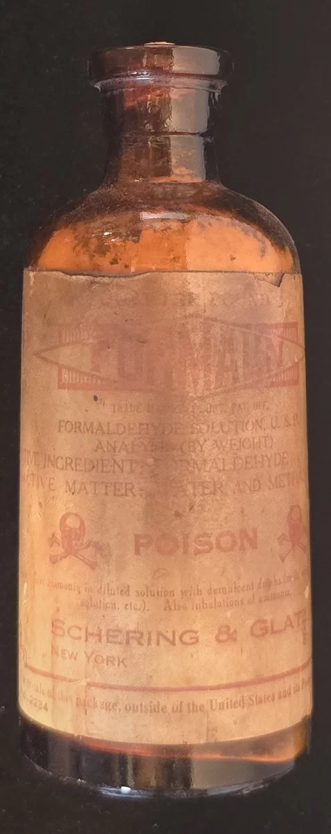 Amber glass bottle labeled Formalin solution, Schering & Glatz, poison symbol visible.