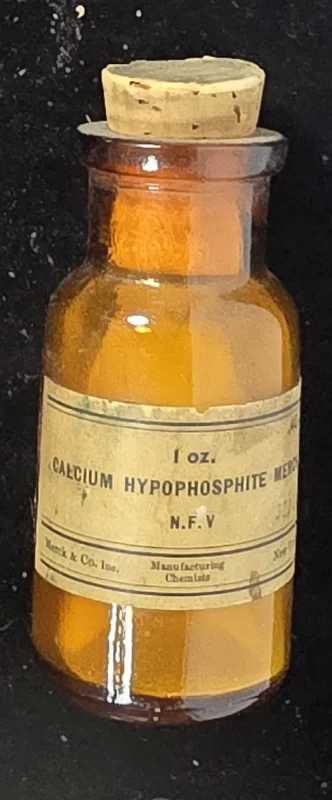 Amber 1 oz Merck & Co. bottle labeled “Calcium Hypophosphite Merck N.F.V.” with original cork.