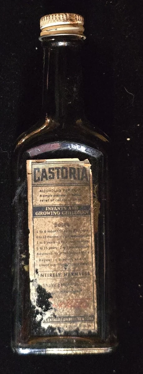 Antique Castoria medicine bottle with partial label, embossed side panel, and original metal screw cap