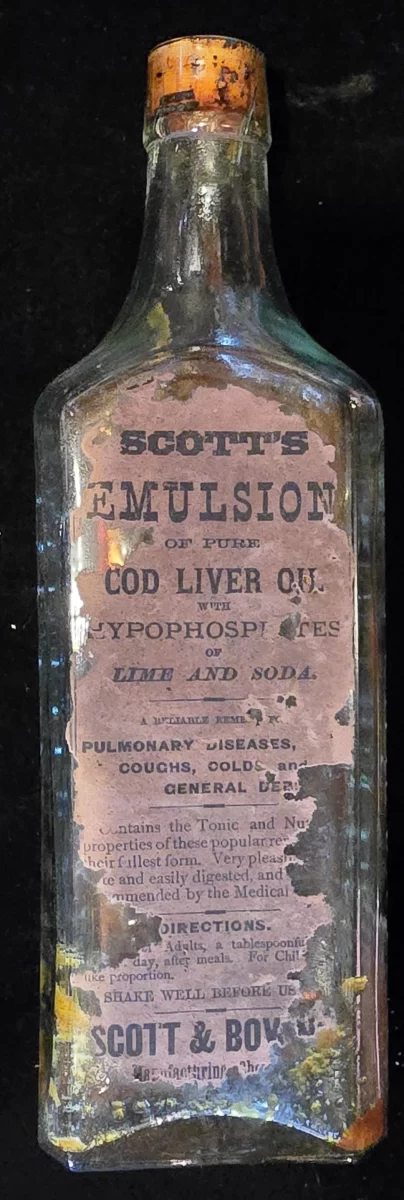 Antique Scott’s Emulsion bottle with partial label, embossed sides, original cork, and visible residue.