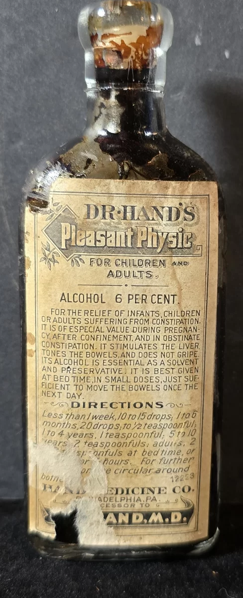 Amber glass bottle of Dr. Hand’s Pleasant Physic with original paper label detailing pediatric and adult dosing instructions and 6 percent alcohol content.