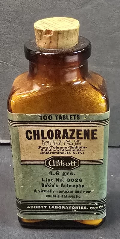 Amber glass bottle of Abbott Chlorazene tablets with original cork stopper and green paper label, early antiseptic pharmaceutical.