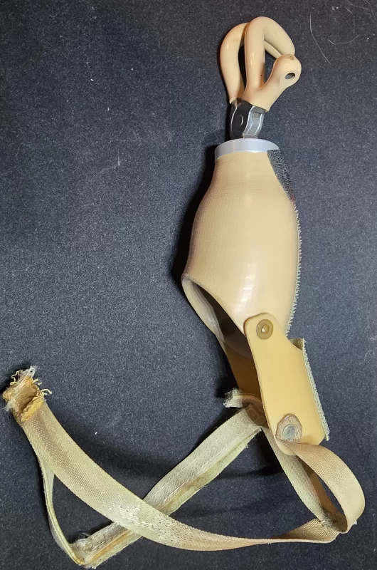Mid-20th century pediatric upper extremity prosthetic arm with three-pronged voluntary-opening terminal device and canvas harness straps