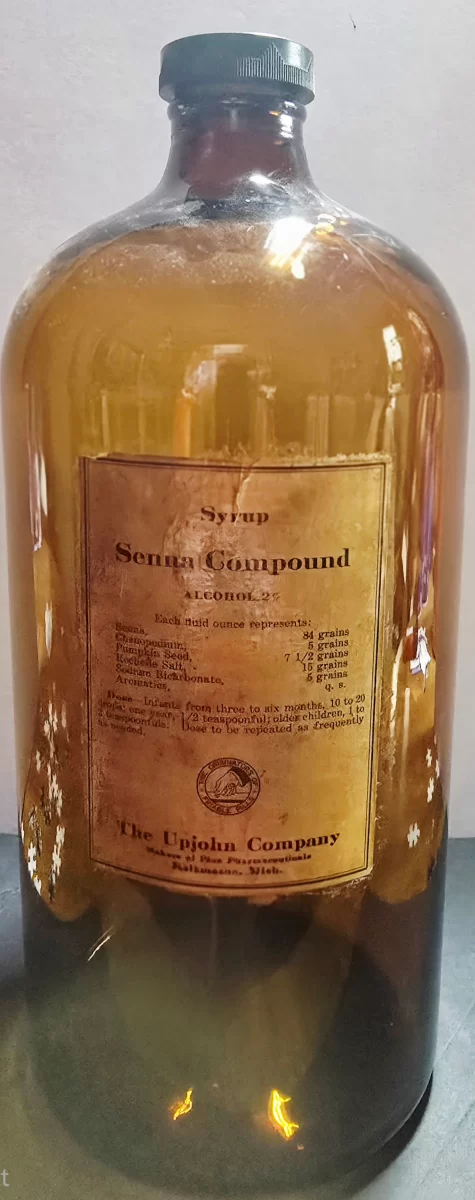 Large amber glass Upjohn Syrup Senna Compound pharmacy stock bottle with original label and embossed metal cap, early 20th century.