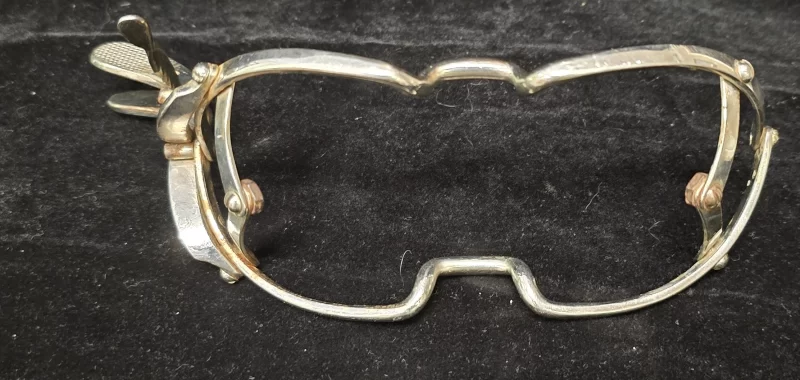 “Jennings-style mouth gag, oval face frame with ratcheting lever, nickel-plated steel, antique surgical instrument”