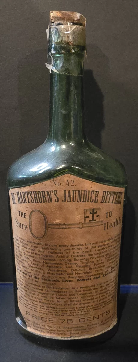 Antique green glass bottle labeled Dr. Hartshorn’s Jaundice Bitters with embossed lettering and original worn paper label