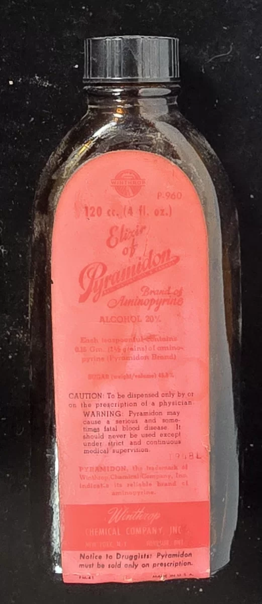 Vintage amber glass Pyramidon aminopyrine elixir bottle by Winthrop Chemical Company with original red prescription warning label.